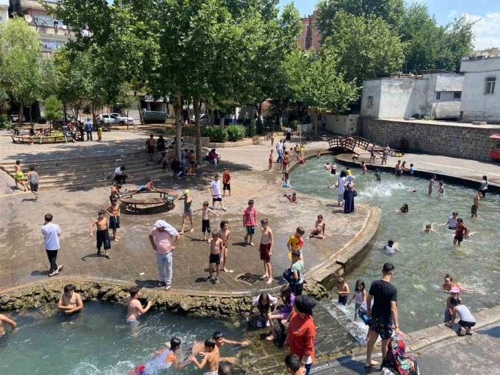 Diyarbakır’da çocuklar ailelerinin nezaretinde süs havuzunda serinliyor