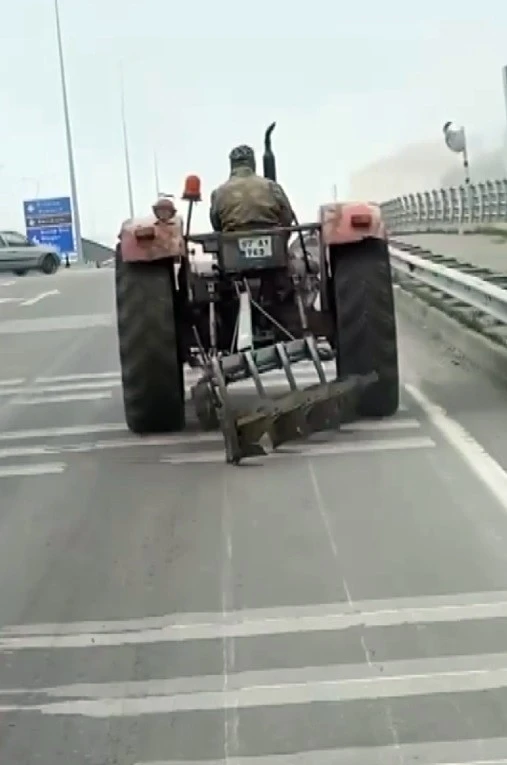 Traktör arkasındaki sabanla asfaltı çizerek karayolunda seyir etti
