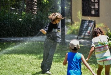 Antalya'da sıcaktan bunalanlar fıskiye ile serinledi, turistler gezerken şemsiye ve şapka kullandı