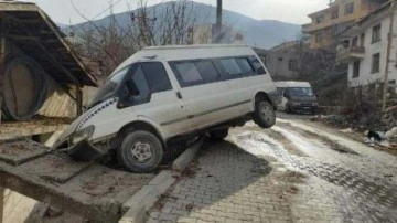 Buzlu yolda kayan minibüs askıda kaldı